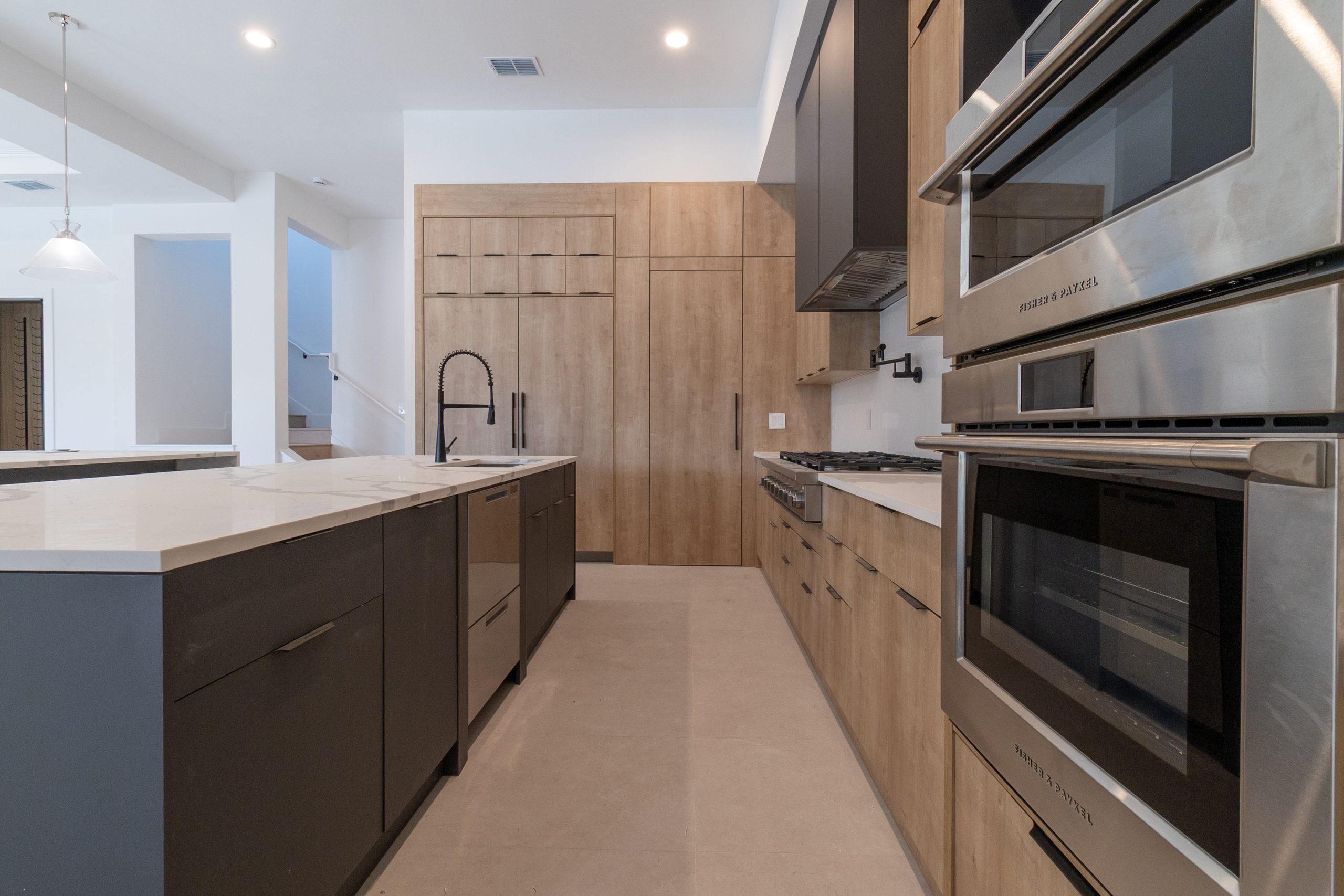 Cozinha americana em casa nos estados unidos, de alto padrão, integrada com varanda, living e área gourmet. Cozinha com tons amadeirados. Puxadores pretos.