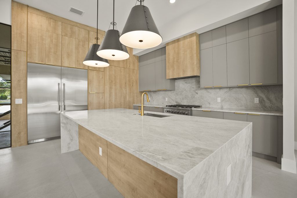 Cozinha americana em casa nos estados unidos, de alto padrão, integrada com varanda, living e área gourmet. Cozinha com tons amadeirados e cinzas. Puxadores pretos.