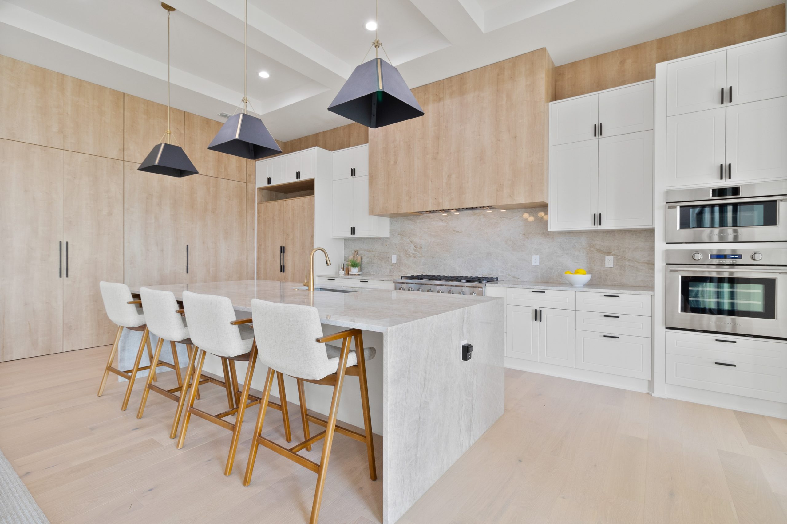 Cozinha americana em casa nos estados unidos, de alto padrão, integrada com varanda, living e área gourmet. Cozinha branca com detalhes amadeirados. Puxadores pretos.