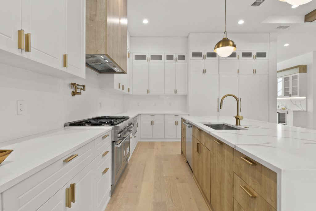 Cozinha americana em casa nos estados unidos, de alto padrão, integrada com varanda, living e área gourmet. Cozinha branca com detalhes amadeirados. Puxadores dourados.