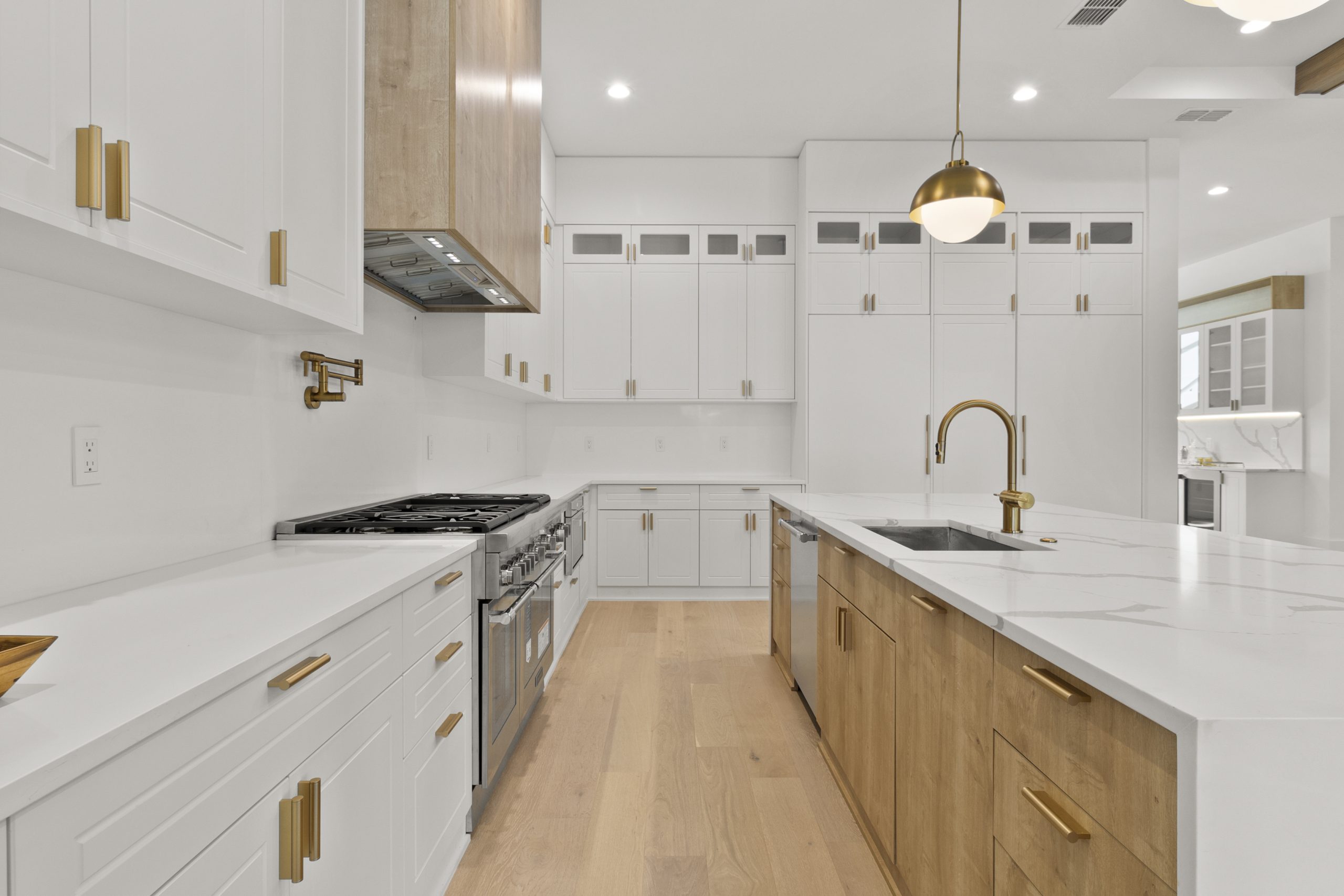 Cozinha americana em casa nos estados unidos, de alto padrão, integrada com varanda, living e área gourmet. Cozinha branca com detalhes amadeirados. Puxadores dourados. Ambientes personalizados de luxo, residência de alto padrão