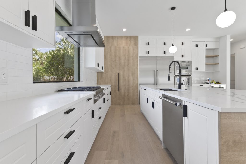 Cozinha americana em casa nos estados unidos, de alto padrão, integrada com varanda, living e área gourmet. Cozinha branca com detalhes amadeirados. Puxadores pretos.