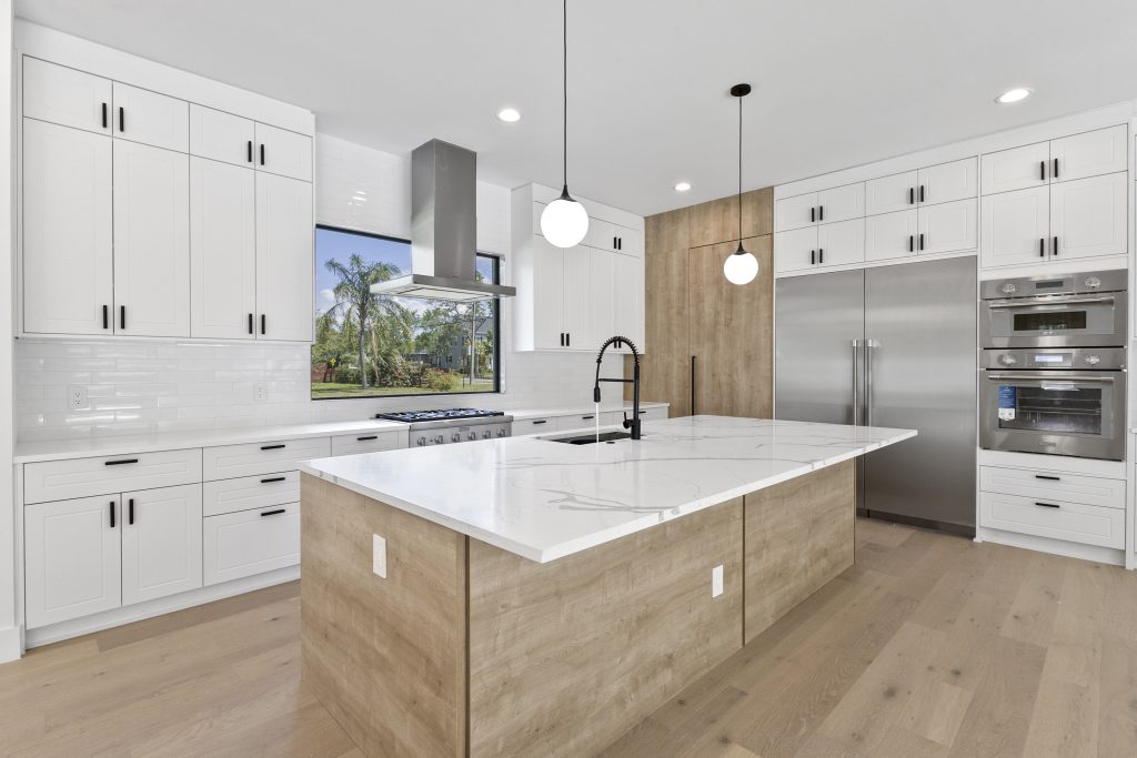 Cozinha americana em casa nos estados unidos, de alto padrão, integrada com varanda, living e área gourmet. Cozinha branca com detalhes amadeirados. Puxadores pretos.