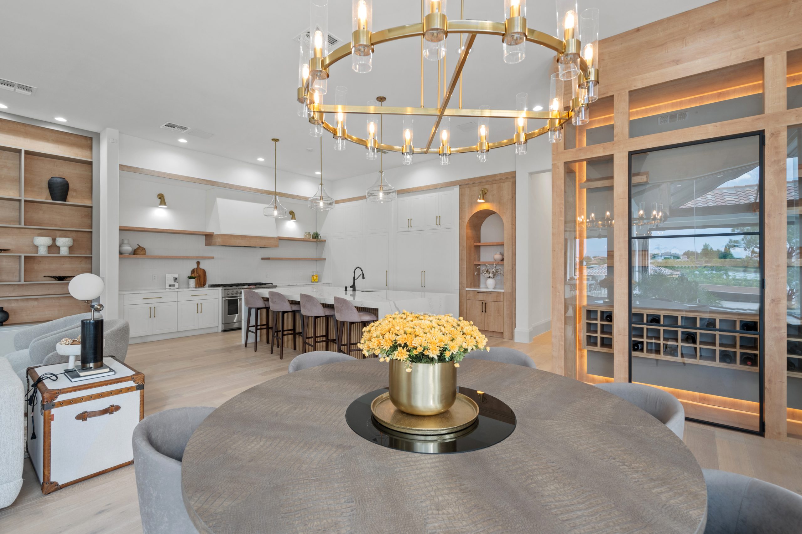 Cozinha americana com ilha em casa nos estados unidos, de alto padrão, integrada com varanda, living e área gourmet. Cozinha branca com detalhes amadeirados e formas orgânicas. Puxadores cromados.