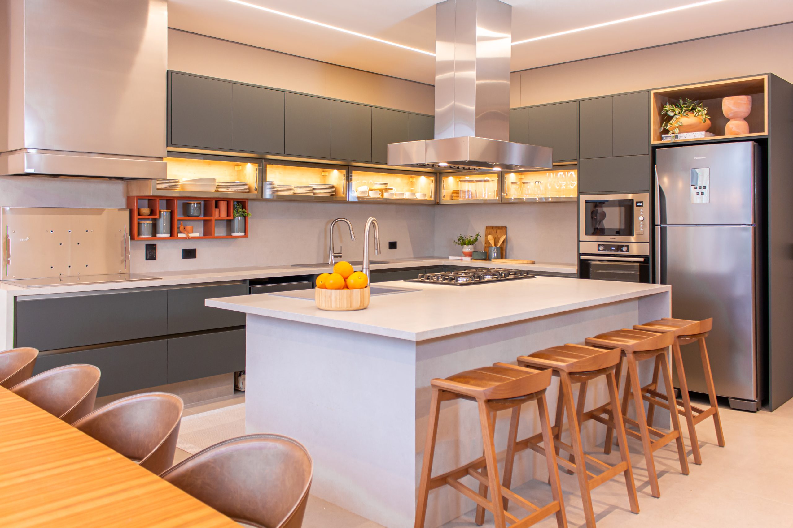 Cozinha com ilha e torre quente. Armários planejados em cor cinza com detalhes em basculante de vidro. Armário de cozinha planejado