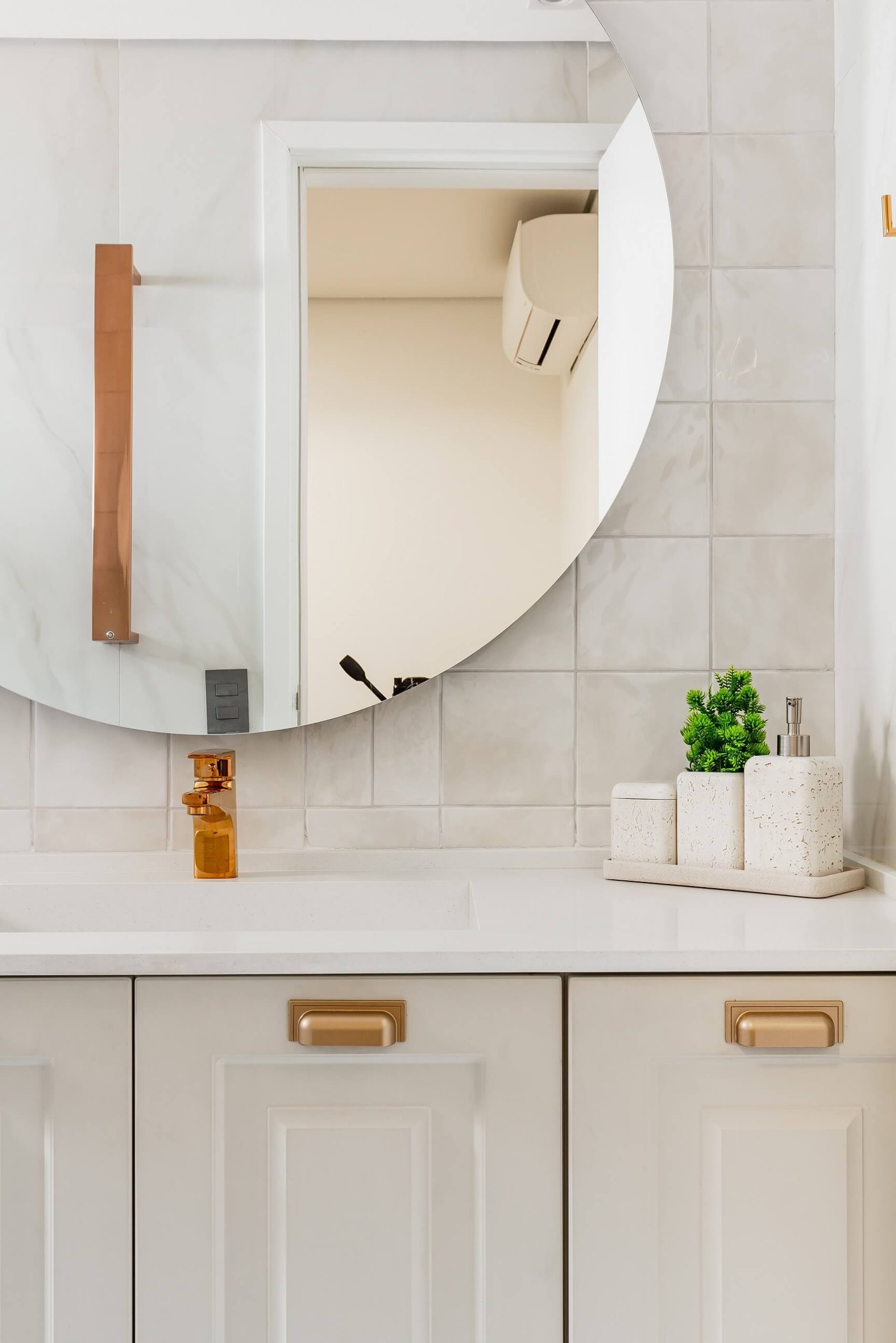 Detalhe de banheiro neutro e delicado, com espelho orgânico e redondo.