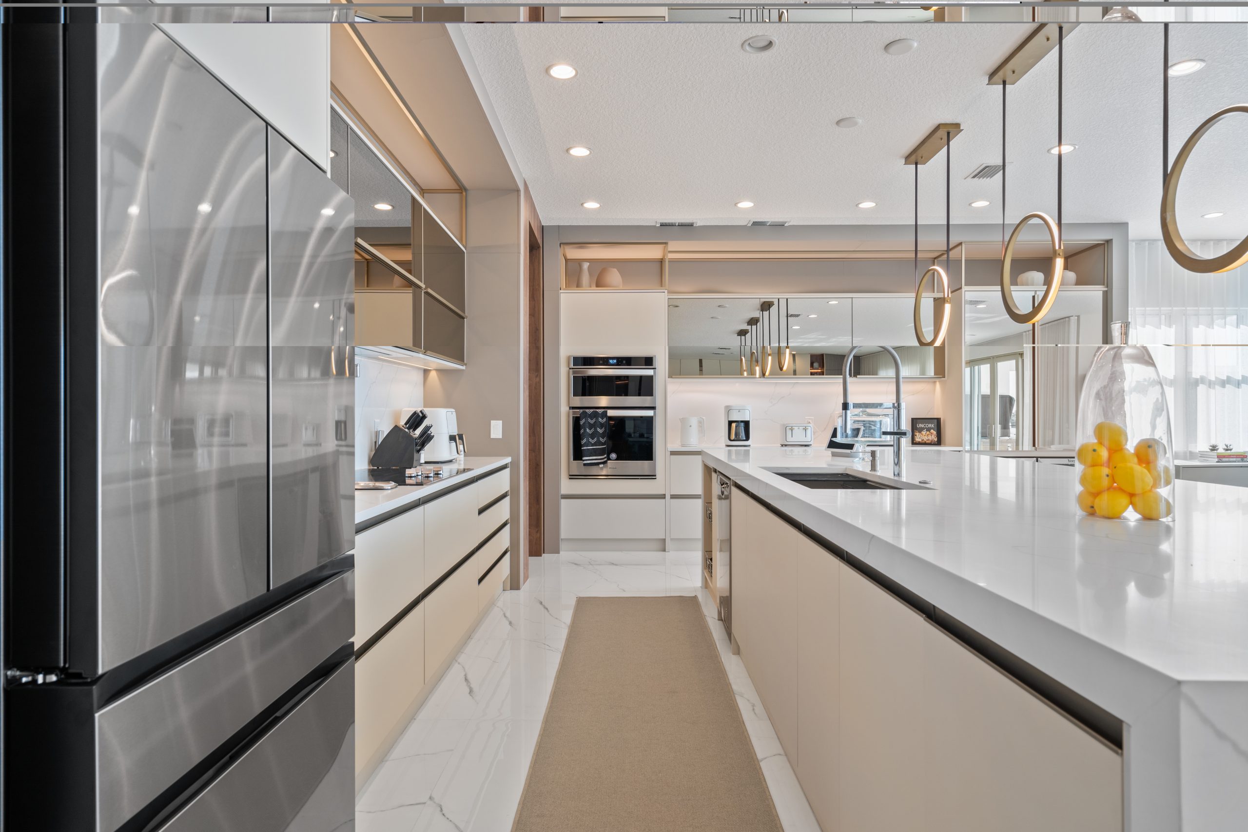 móveis planejados para cozinha luxuosa nos estados unidos, em tons claros com portas de espelho refletivas com ilha ampla e marmore branco.