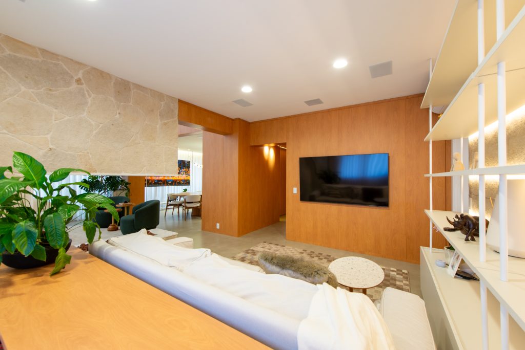 Living íntimo com mobiliário personalizado de alto padrão, pedra natural, tons amadeirados e um design afetivo intimista