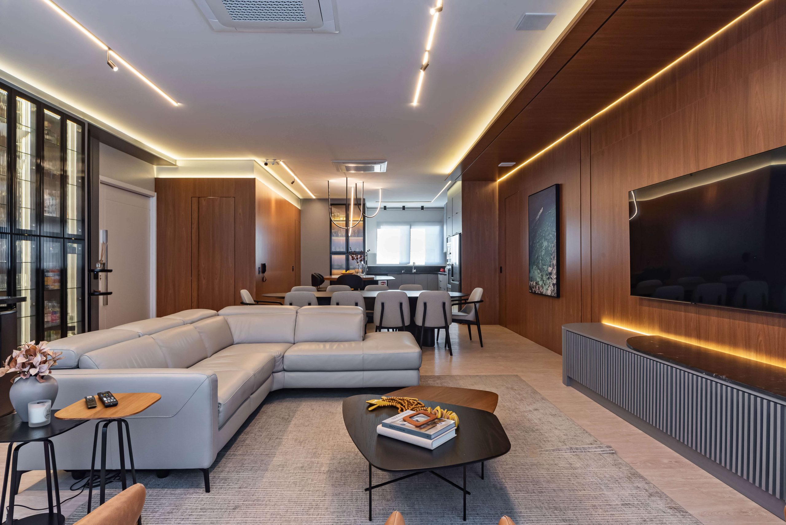 Sala integrada com painéis planejados Finger e mobiliário sob medida. O uso de madeira FREIJÓ e iluminação quente cria uma atmosfera de conforto, sofisticação e equilíbrio estético. Sala planejada de alto padrão, painéis sob medida, design de interiores Finger. Móveis orgânicos e linhas fluídas. Ambiente integrado com cozinha, churrasqueira, adega e bar.
