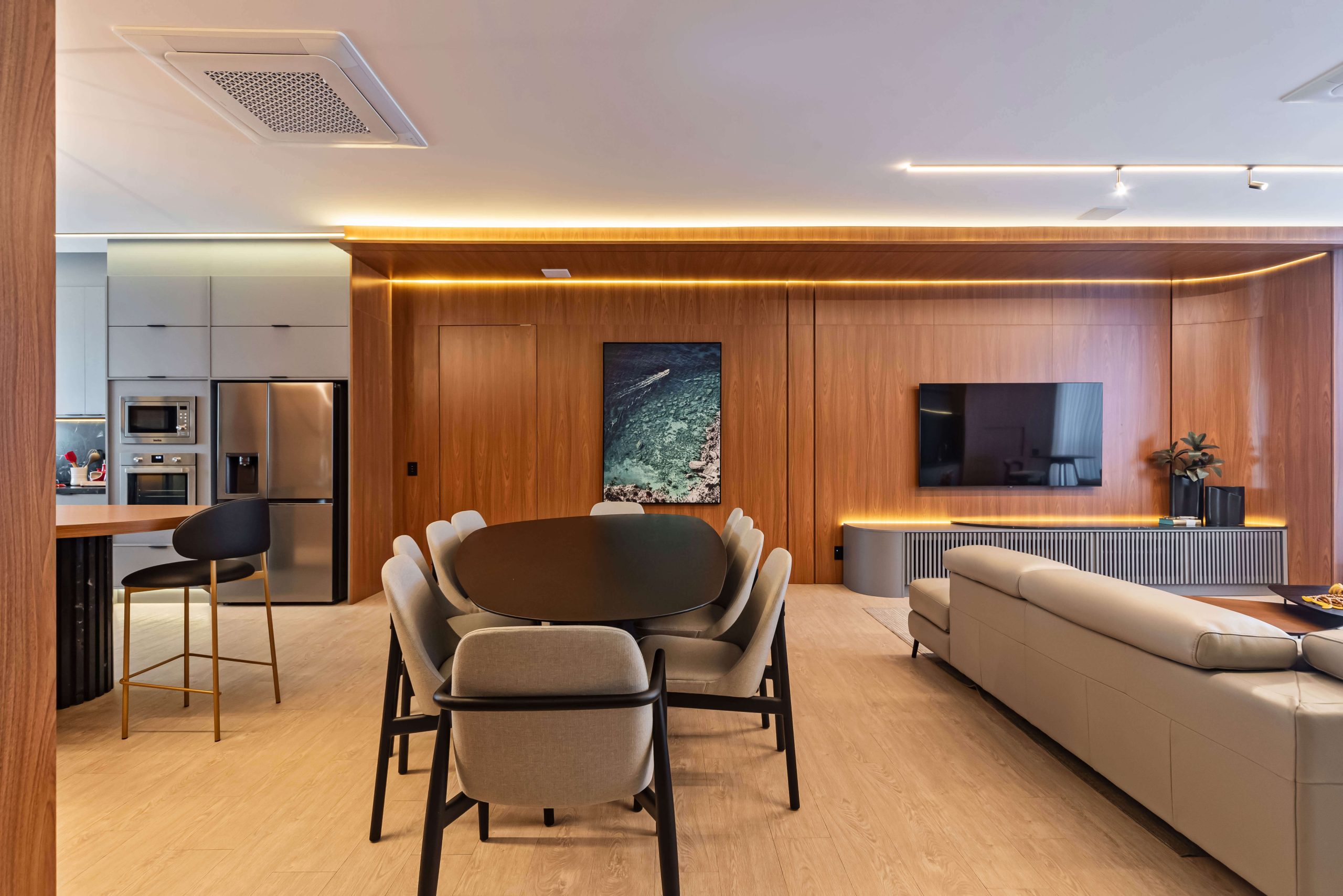 Sala integrada com painéis planejados Finger e mobiliário sob medida. O uso de madeira FREIJÓ e iluminação quente cria uma atmosfera de conforto, sofisticação e equilíbrio estético. Sala planejada de alto padrão, painéis sob medida, design de interiores Finger. Móveis orgânicos e linhas fluídas. Ambiente integrado com cozinha, churrasqueira, adega e bar.