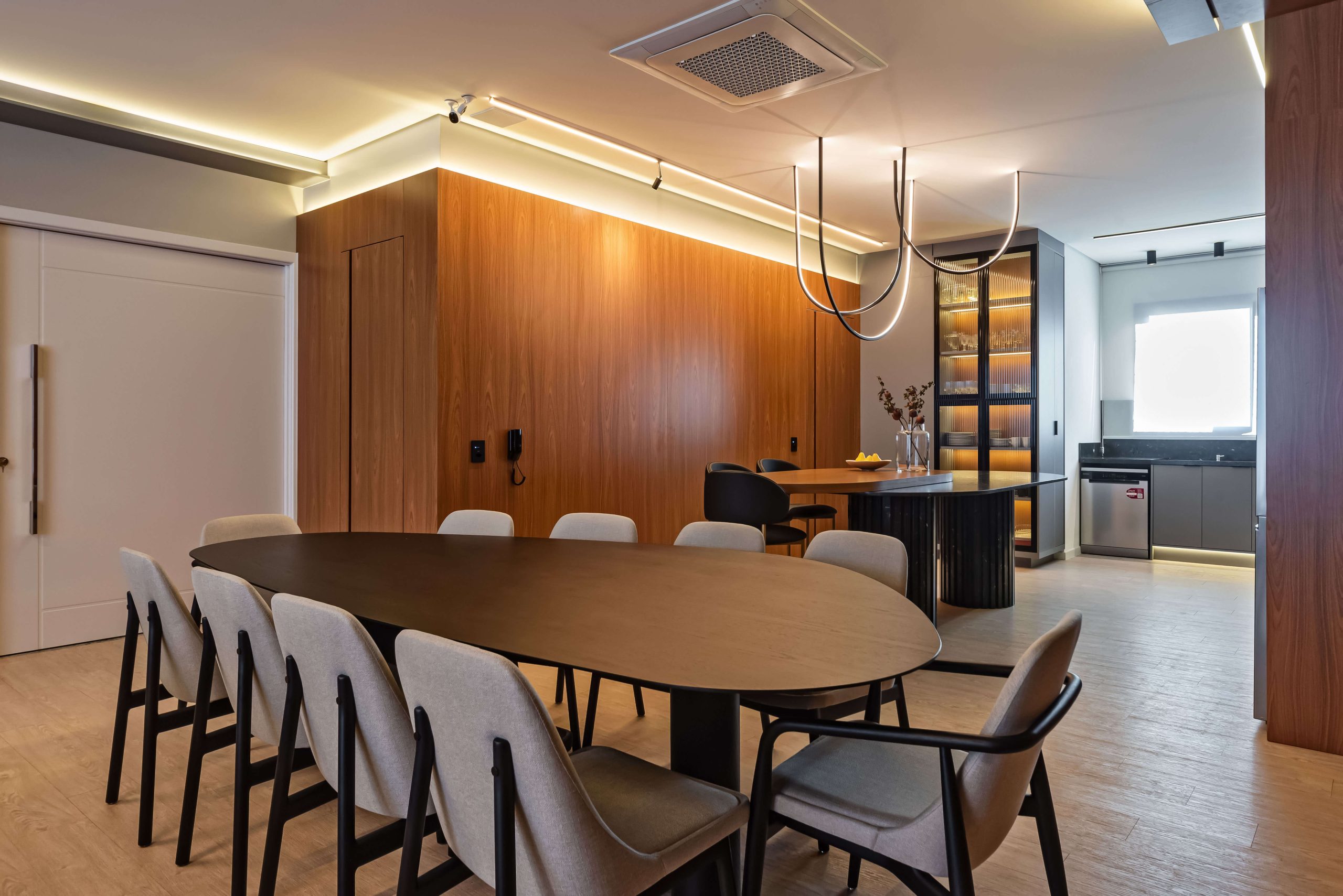 Ambiente gourmet Finger com integração entre cozinha e área social. Móveis planejados em tons neutros e texturas sofisticadas criam uma atmosfera elegante e acolhedora, perfeita para receber com conforto. SEO foco: ambiente gourmet planejado, integração de espaços, móveis Finger. Cozinha no tom cinza, mesa em mármore preto com pés ripados e living amplo no padrão freijó.