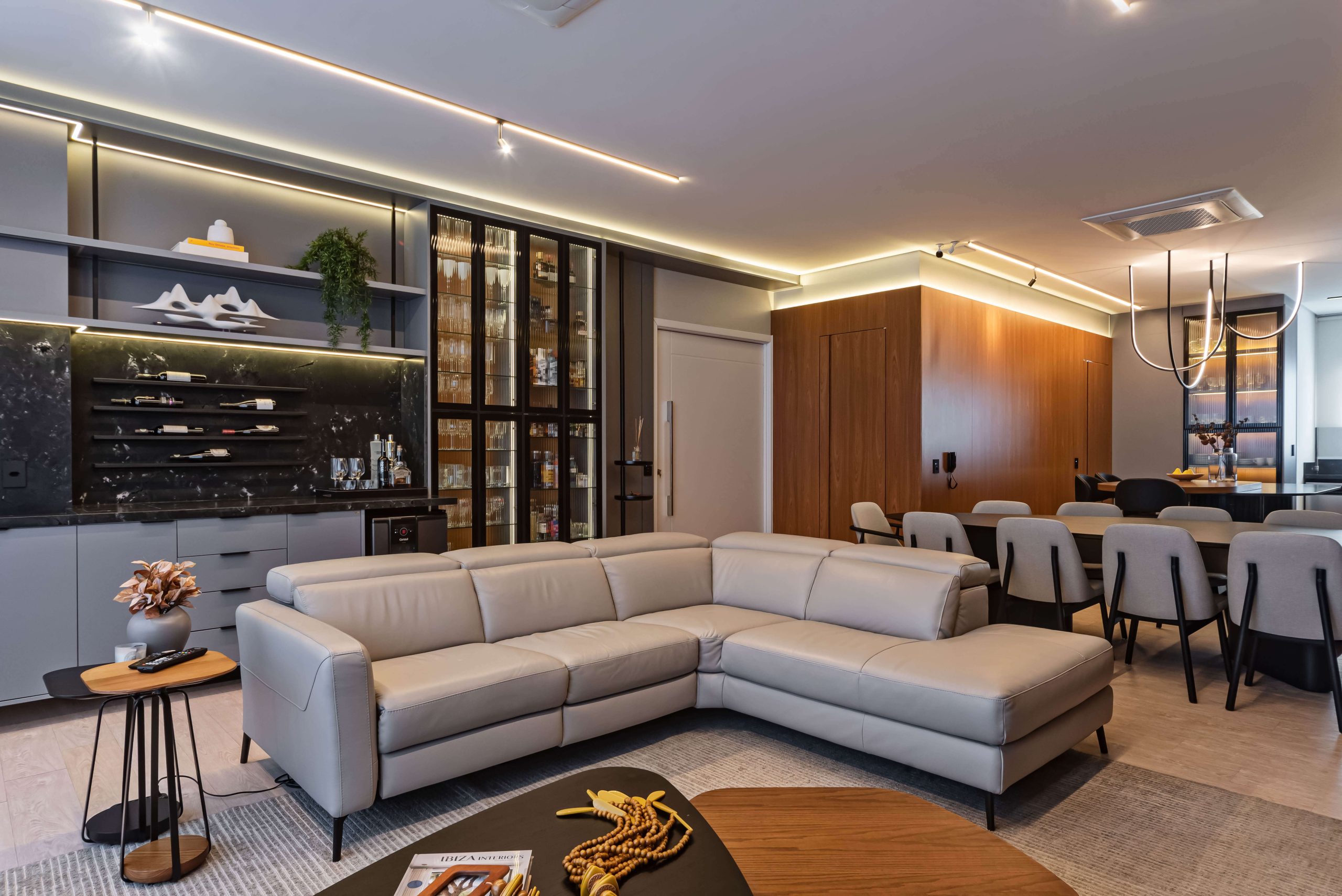 Sala integrada com painéis planejados Finger e mobiliário sob medida. O uso de madeira FREIJÓ e iluminação quente cria uma atmosfera de conforto, sofisticação e equilíbrio estético. Sala planejada de alto padrão, painéis sob medida, design de interiores Finger. Móveis orgânicos e linhas fluídas. Ambiente integrado com cozinha, churrasqueira, adega e bar.