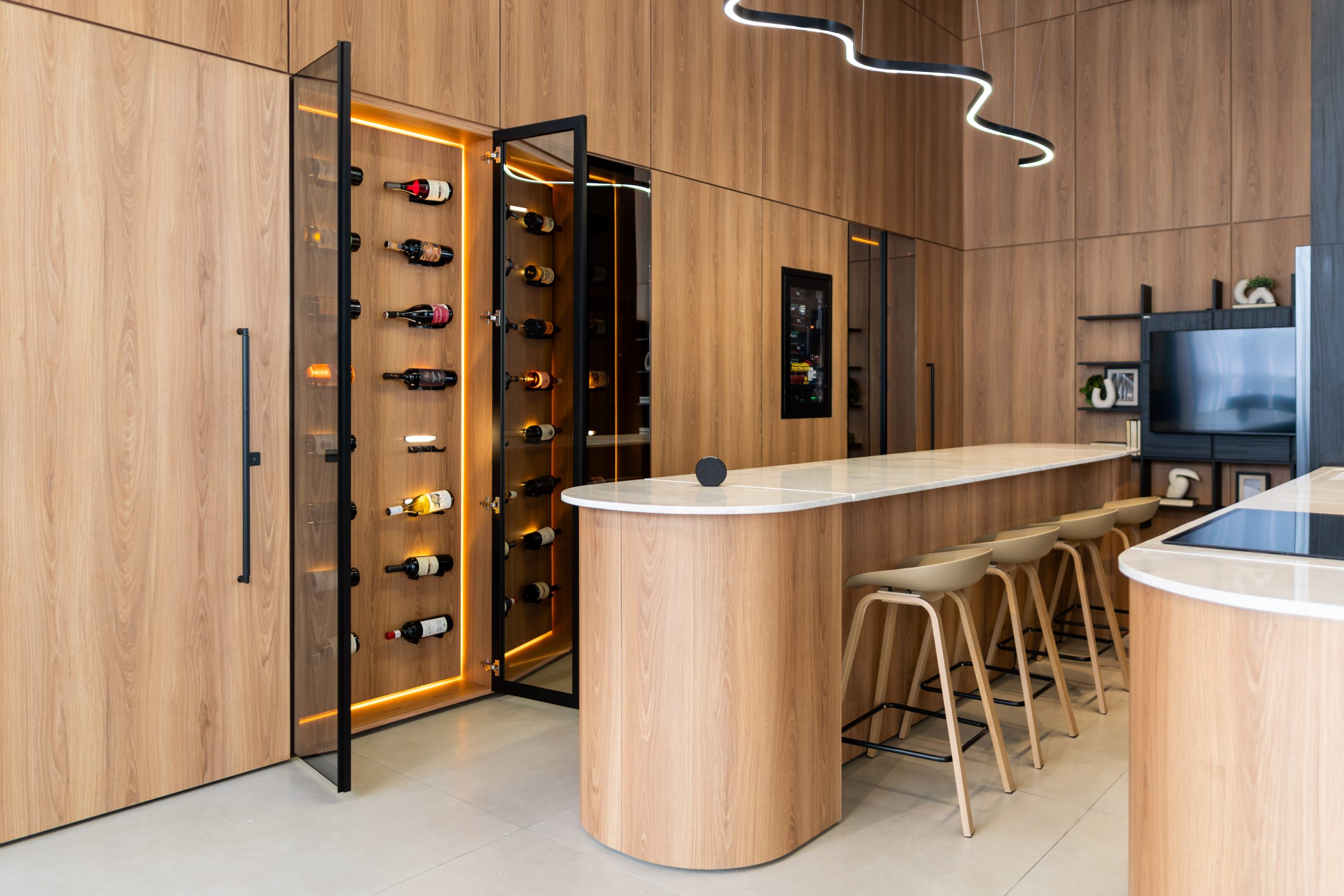 Cozinha Edles com ilha curva e arredondada, com adega e suporte de vinhos da Villaggio. Tendência de cozinha 2026