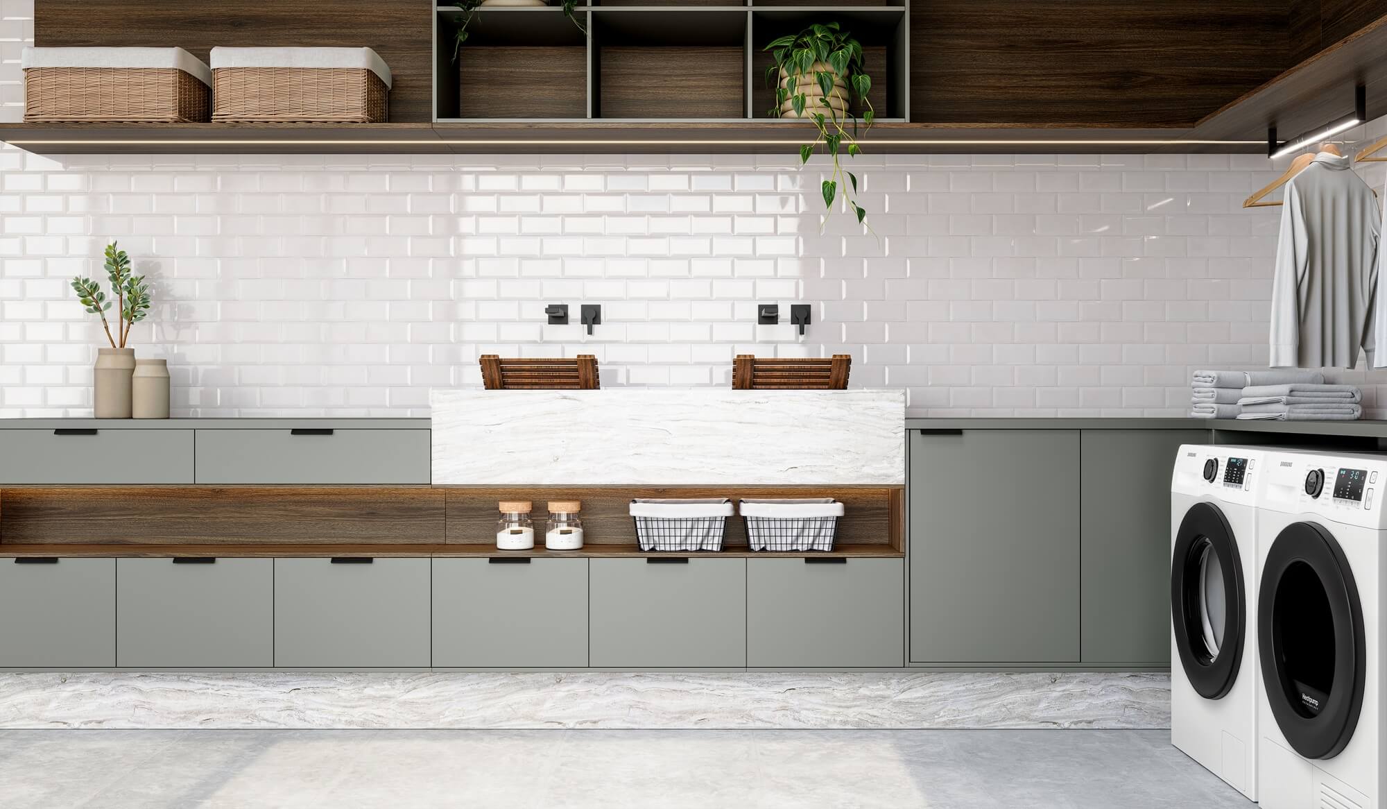 A nova Coleção Zeit da Finger Ambientes Personalizados, oferece uma linha de móveis planejados de alto padrão para ambientes que valorizam o design, o conforto, bem-estar e a funcionalidade. A nova coleção é um convite para experimentar e sentir o tempo e a vida. Esse ambiente mostra uma lavanderia planejada sofisticada, com dois tanques, duas máquinas de lavar, cabides para roupas passadas e espaço para trabalho e armazenar os itens de higiene, estilo que destaca a brasilidade, design afetivo, a arquitetura vernacular e valorização das texturas. Detalhe para a iluminação embutida nas prateleiras. A composição de cores traz uma madeira mais escura cheio de personalidade com o padrão mais neutro Moos, cinza com fundo esverdeado, fazendo uma conexão com a natureza.