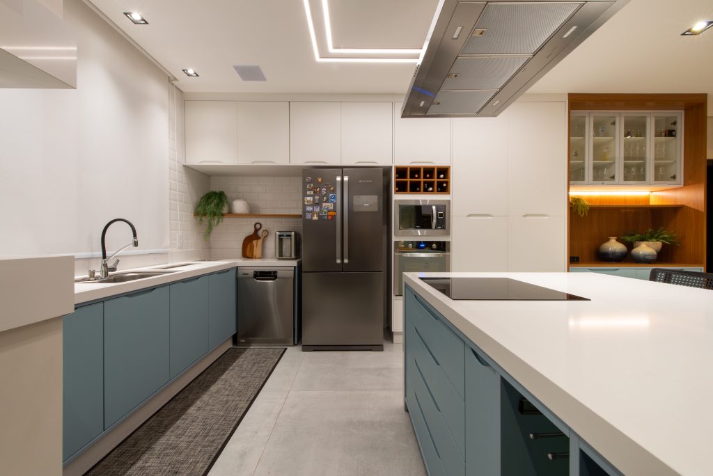 Cozinha Gourmet com acesso pra área externa em azul claro indigo (dusk) com branco e madeira Freijó. Cozinha com ilha ampla. Espaço gourmet