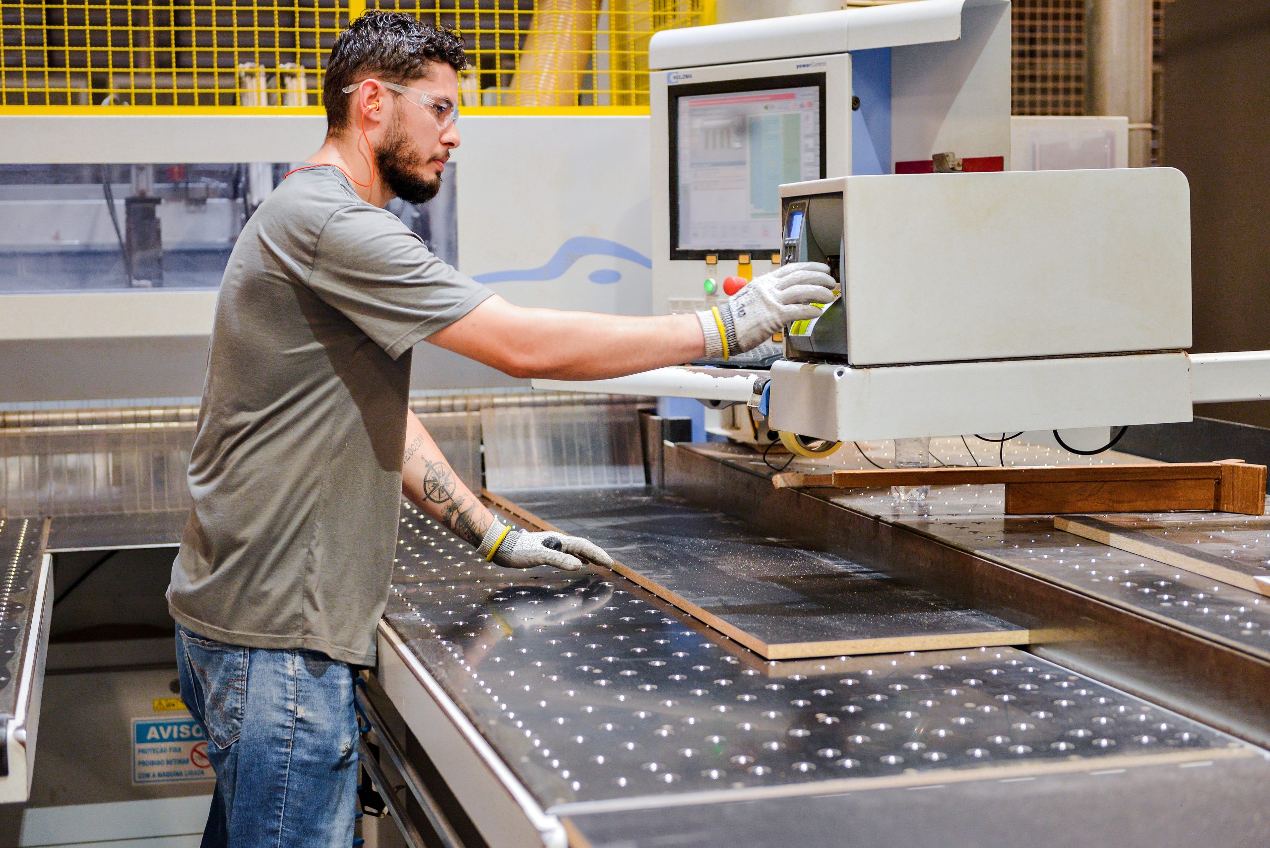 A foto mostra visão aérea interna da fábrica da finger ambientes personalizados, onde móveis planejados de alto padrão são produzidos com inovação, tecnologia e processos bem estruturados. Detalhe do processo de corte otimizado para produção de móveis sustentáveis.