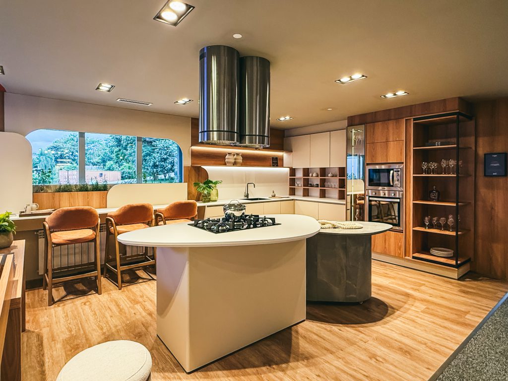 Showroom Zeithaus - Finger Ambientes Personalizados. Cozinha Planejada com Ilha, sistema Furn Spin Giratório. Formas orgânicas, prateleira com iluminação embutida, Handless MDF, Cristaleira, Porta Frame. Padrão Edles e Ivory.