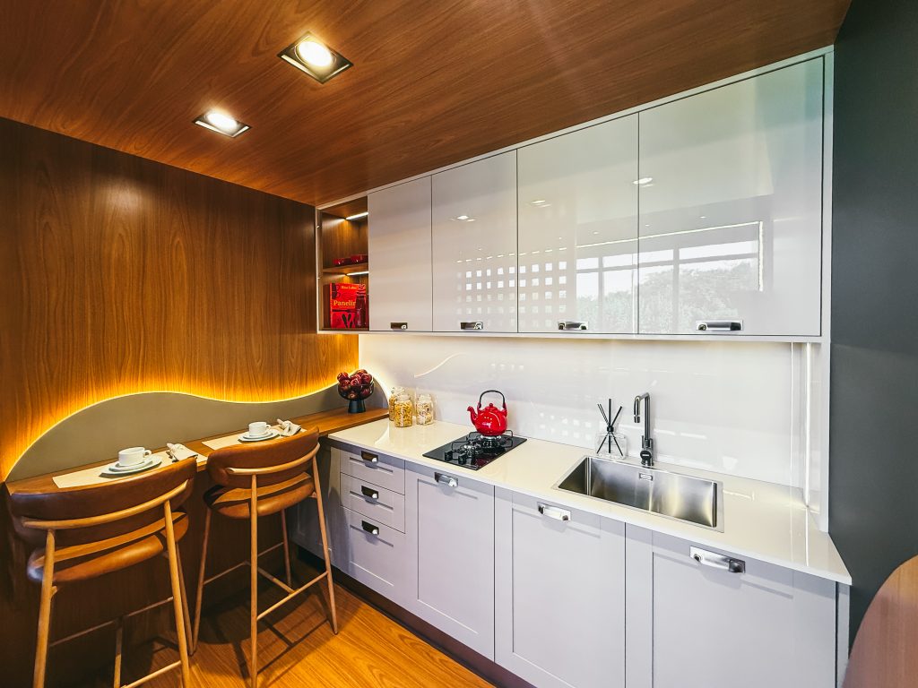 Showroom Zeithaus - Finger Ambientes Personalizados. Cozinha Planejada compacta com bancada pra refeições rápidas. Painel muxarabi, frente SHAKER, padrão Freijo com Kakao e alto brilho. Cozinha de canto planejada