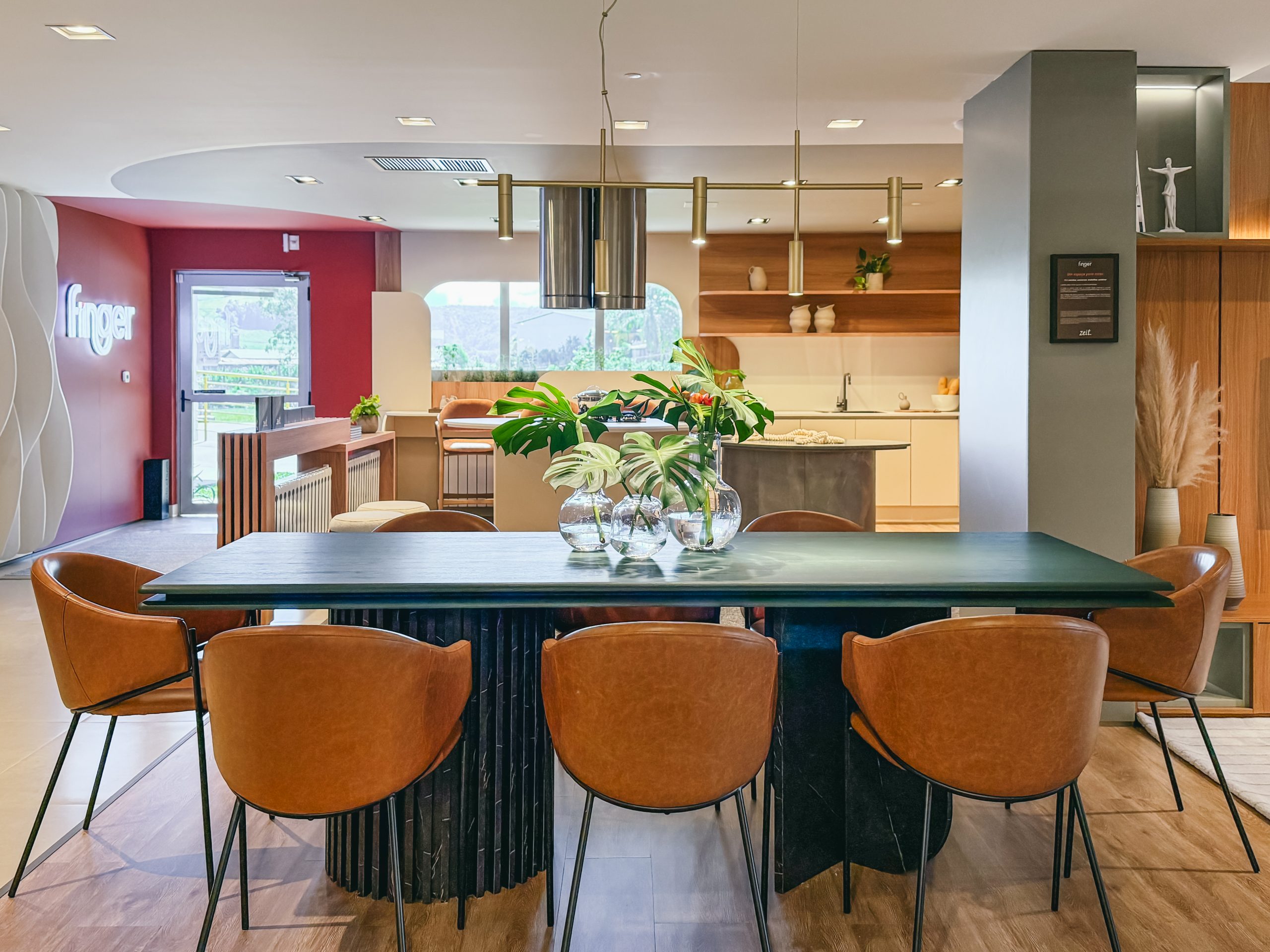 Showroom Zeithaus - Finger Ambientes Personalizados. Cozinha Planejada com Ilha, sistema Furn Spin Giratório. Formas orgânicas, prateleira com iluminação embutida, Handless MDF, Cristaleira, Porta Frame. Padrão Edles e Ivory. Com mesa com borda arredondada.