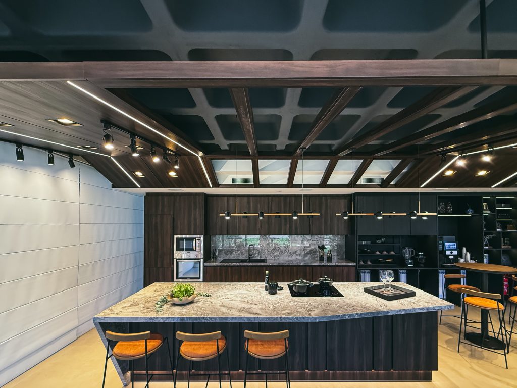 Showroom Zeithaus - Finger Ambientes Personalizados. Cozinha Elegante e sofisticada com padrões escuros com ilha e teto industrial. Sistema Furn Spin giratório. Porta Frame. Padrões Silent e Eben. Iluminação embutida. tipos de puxadores