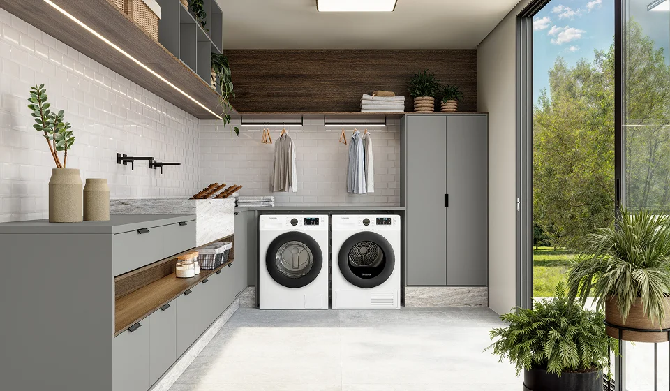 Lavanderia planejada funcional com armários cinza, bancada em mármore, nichos organizadores e iluminação sob os móveis