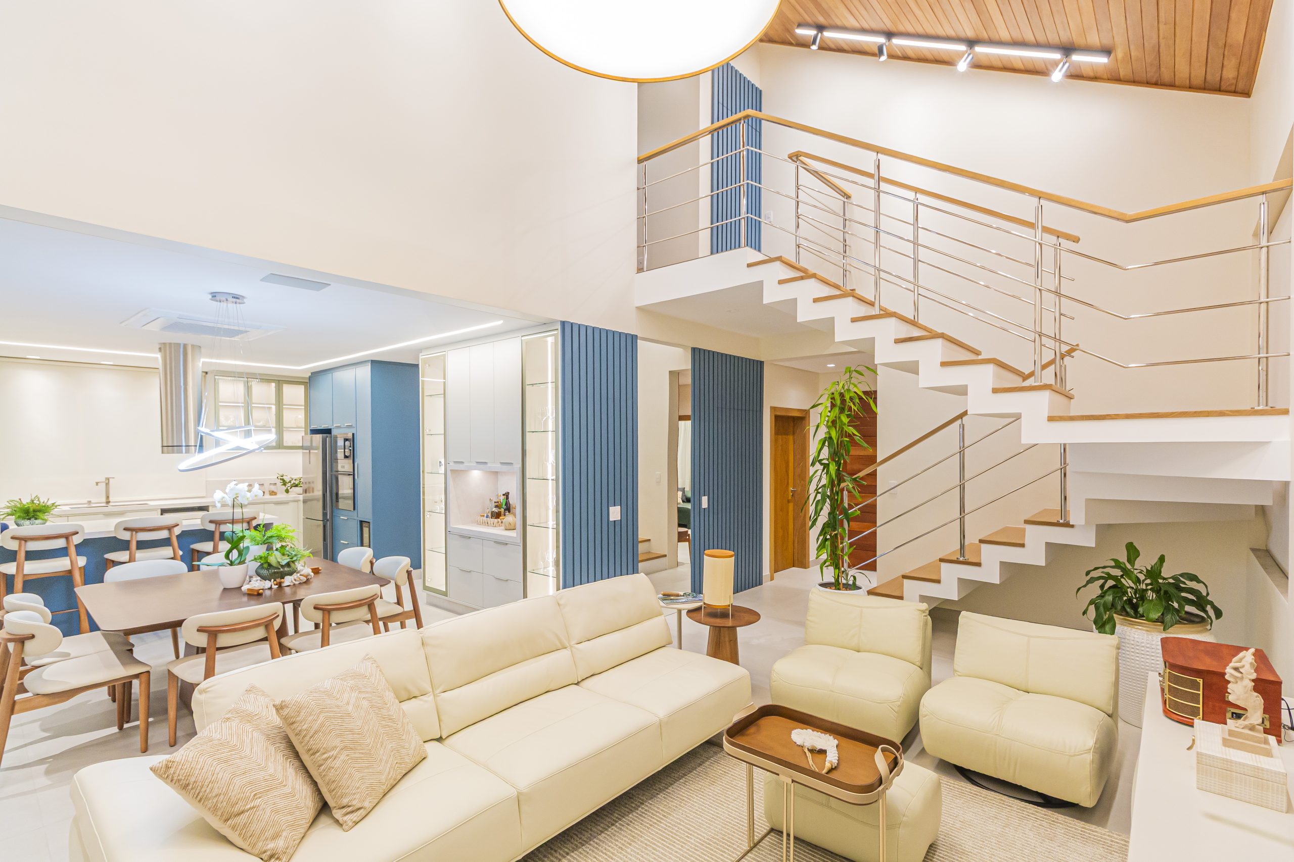 Living integrado com cozinha, em tons claros e azul, sala de jantar e cristaleira