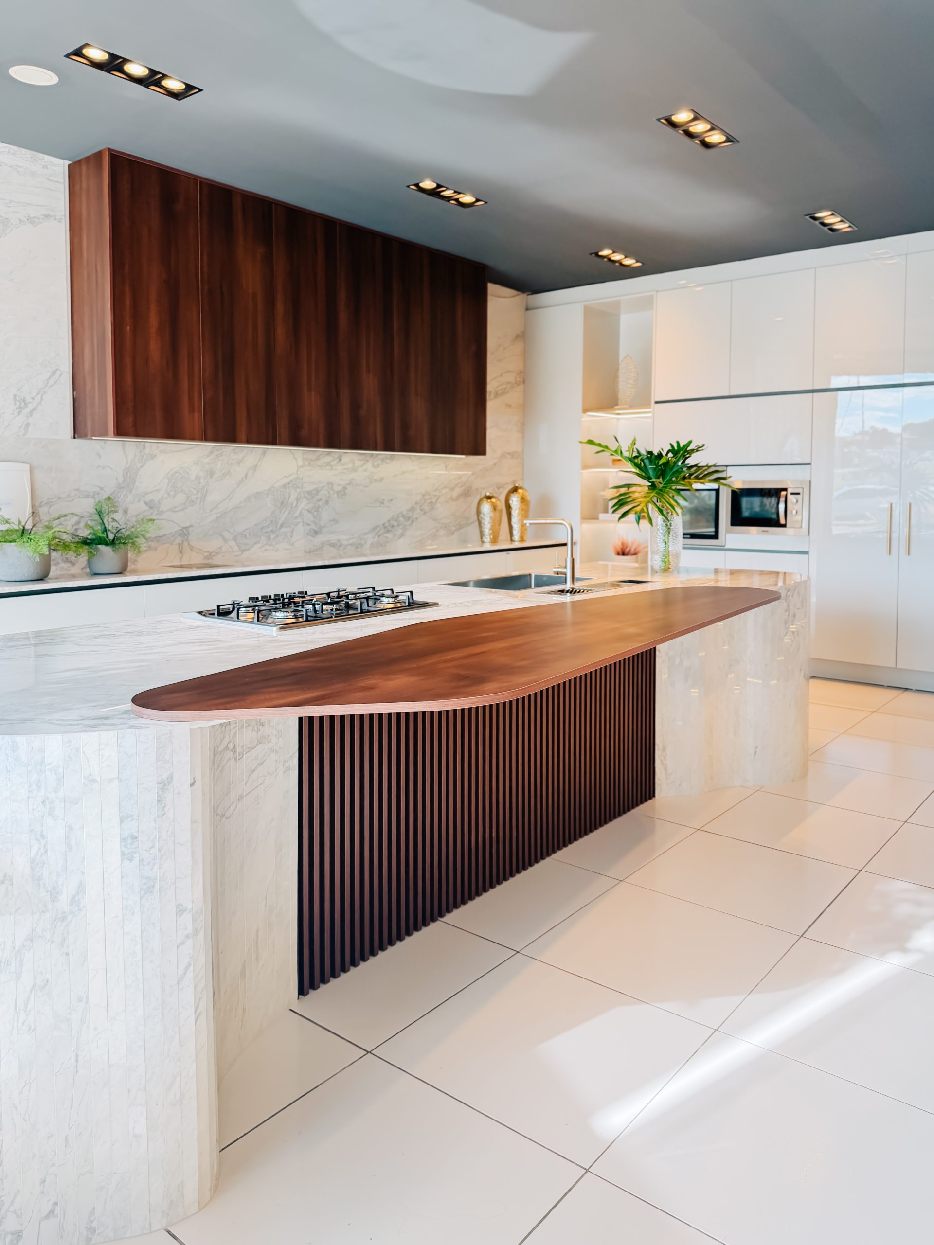 Design de interiores curvas e formas organicas dominam. Linha Kurve. Cozinha planejada com ilha estilo contemporâneo e sofisticado de alto padrão em tons neutros com toque de madeira escura.