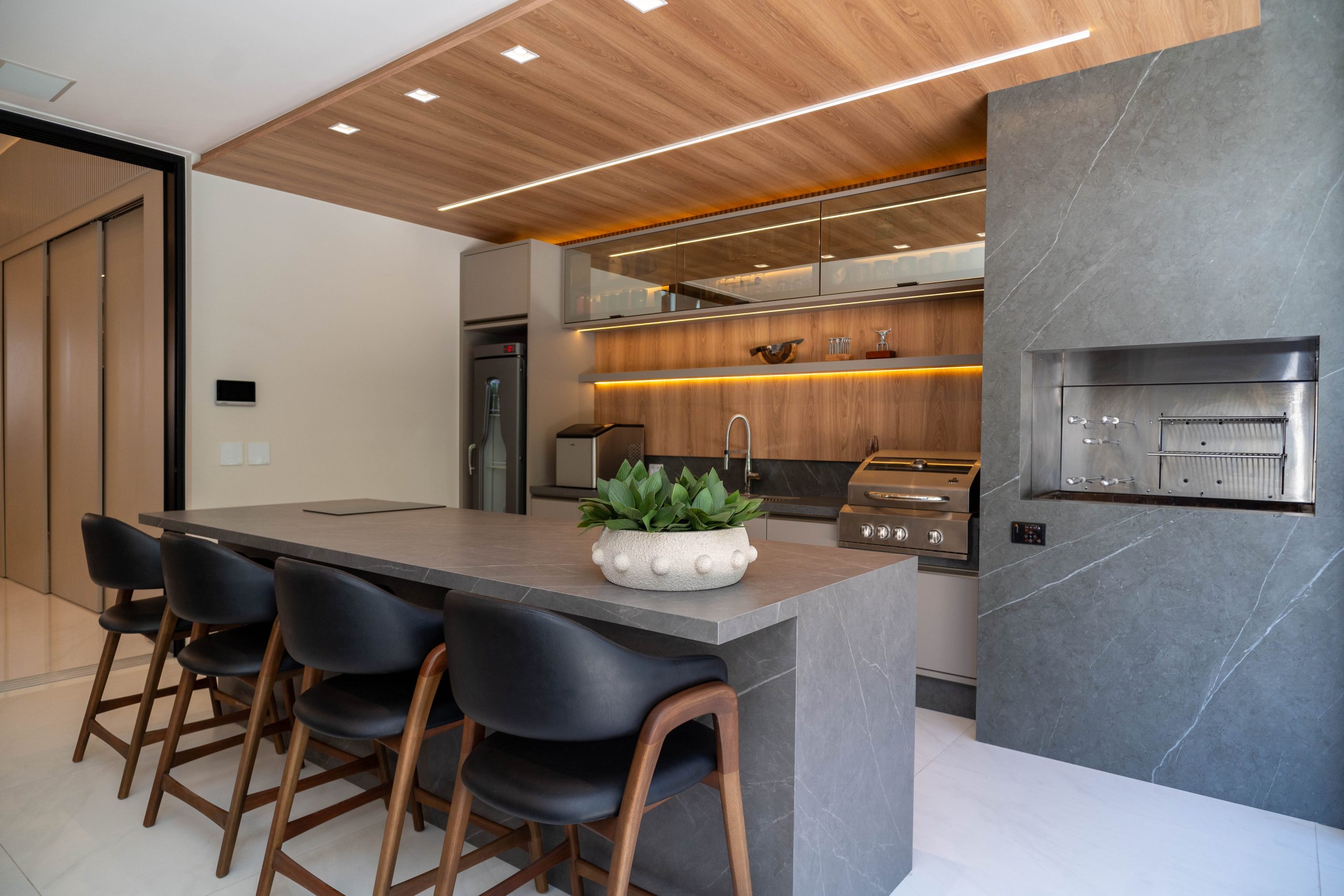 Espaço gourmet com churrasqueira, bancada e churrasqueira e iluminação com led.