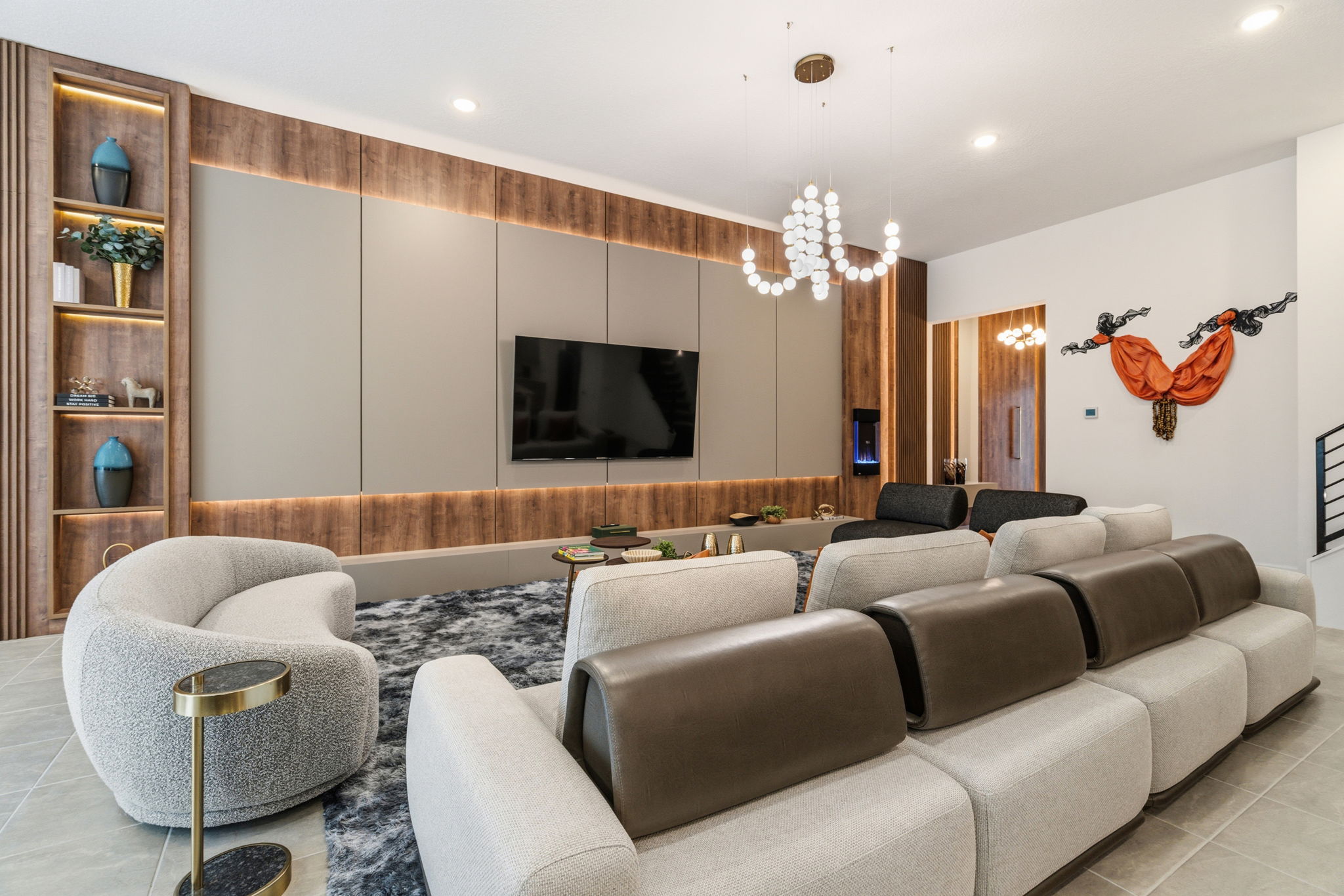 Móveis planejados para Sala de estar sofisticada, destacada por um rack planejado estilo bancada baixa integrada ao painel, composto por placas modulares em tom neutro com moldura amadeirada e iluminação LED indireta superior e inferior, além de uma estante lateral com nichos iluminados.