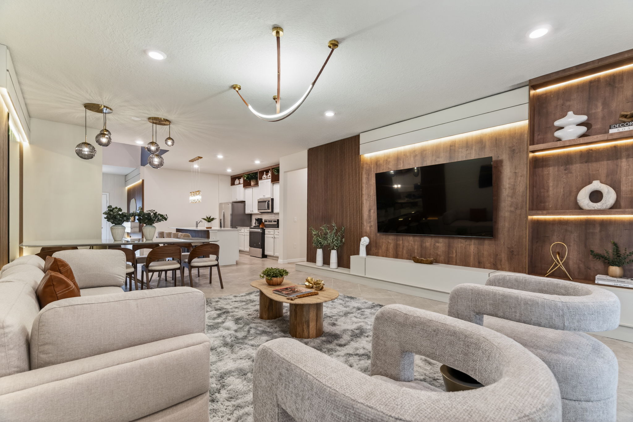 Móveis planejados para Sala de estar integrada e elegante, destacada por um rack planejado suspenso em tom claro, conectado a um painel central amadeirado retroiluminado com LED, ladeado por painel ripado e nichos decorativos abertos.