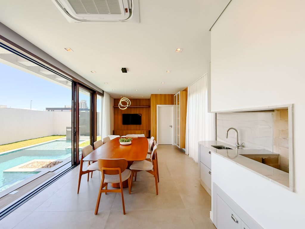 Gabinete de cozinha - cozinha aberta em tons claros com ilha integrada a área externa com piscina.