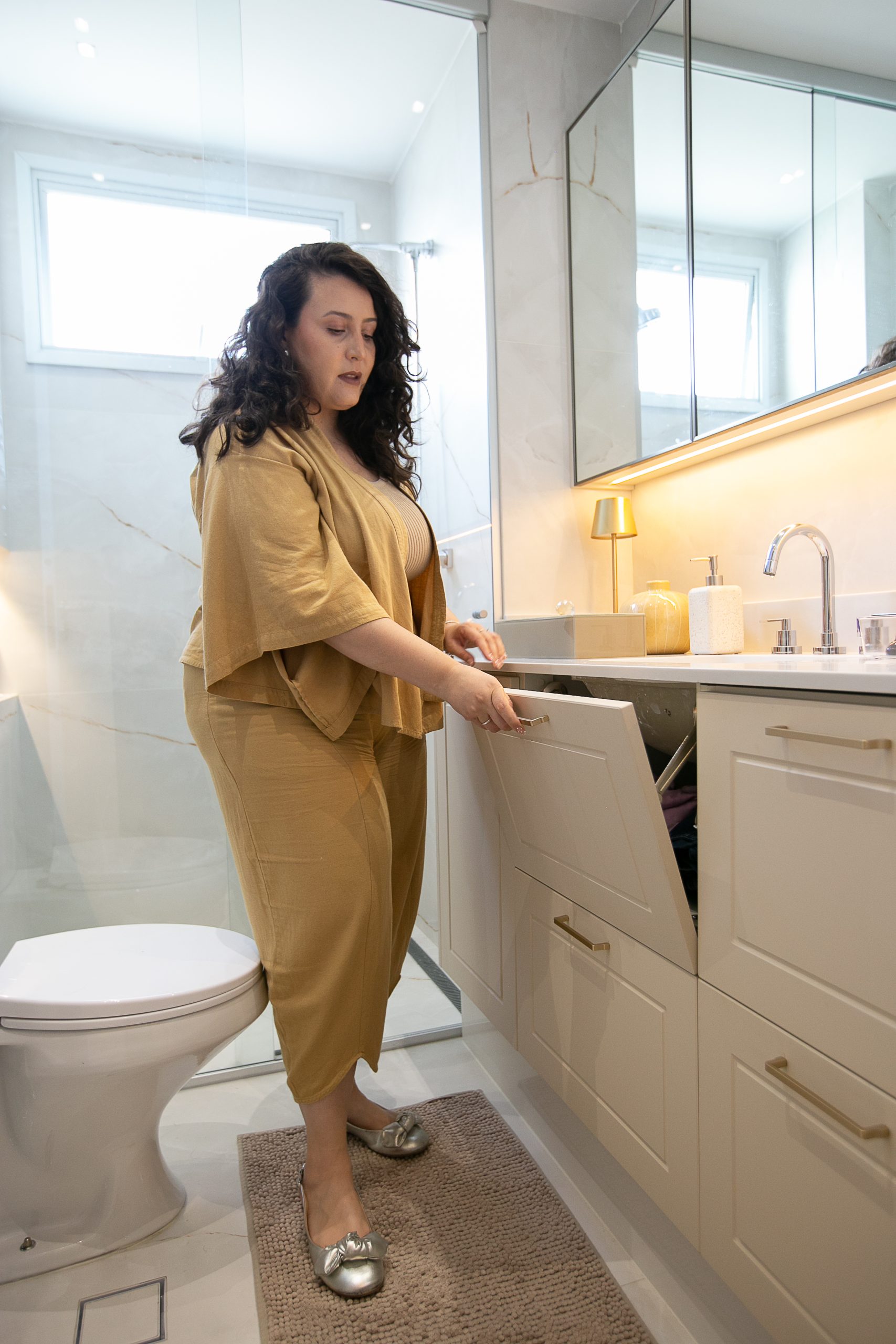 Banheiro moderno com armários branco e detalhes em dourado